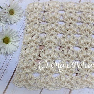 May include: Cream-colored, crocheted square with a floral pattern. The handmade piece features a repeating design of textured, fan-like shapes. The text "(c) Olga Poltava" is visible. White daisies are arranged on a light wood surface.
