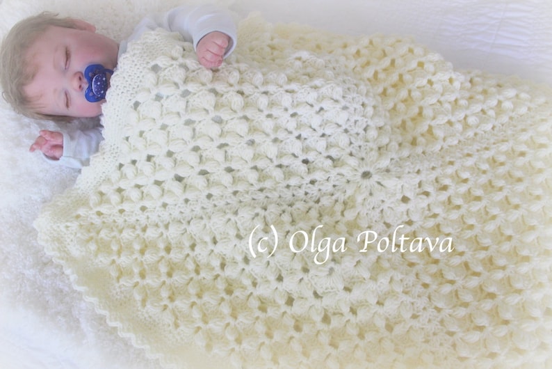 Pode incluir: Um cobertor de beb&eacute; branco de croch&ecirc; com um padr&atilde;o floral delicado. O cobertor &eacute; feito com um fio macio e &eacute; perfeito para manter um beb&eacute; quente e confort&aacute;vel.