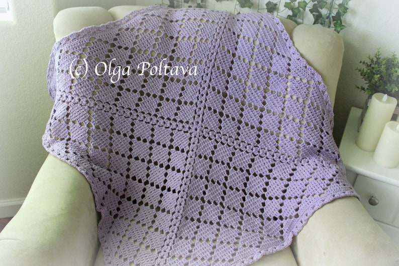 Puede incluir: Una manta de ganchillo de color lavanda con un patr&oacute;n de diamantes. La manta est&aacute; drapeada sobre una silla.