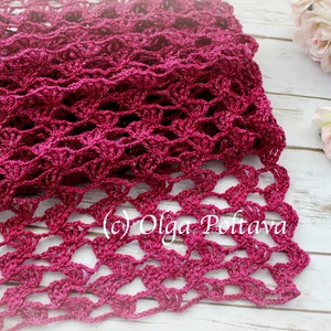 May include: A handmade, open-weave scarf in a deep magenta hue. The scarf features a delicate, lacy pattern, with a scalloped edge. The texture is intricate, and the yarn has a subtle sheen. The copyright symbol and the name "Olga Poltava" are visible.