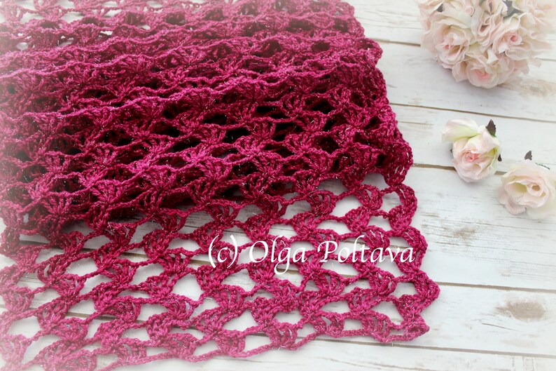 May include: A handmade, open-weave scarf in a deep magenta hue. The scarf features a delicate, lacy pattern, with a scalloped edge. The texture is intricate, and the yarn has a subtle sheen. The copyright symbol and the name "Olga Poltava" are visible.