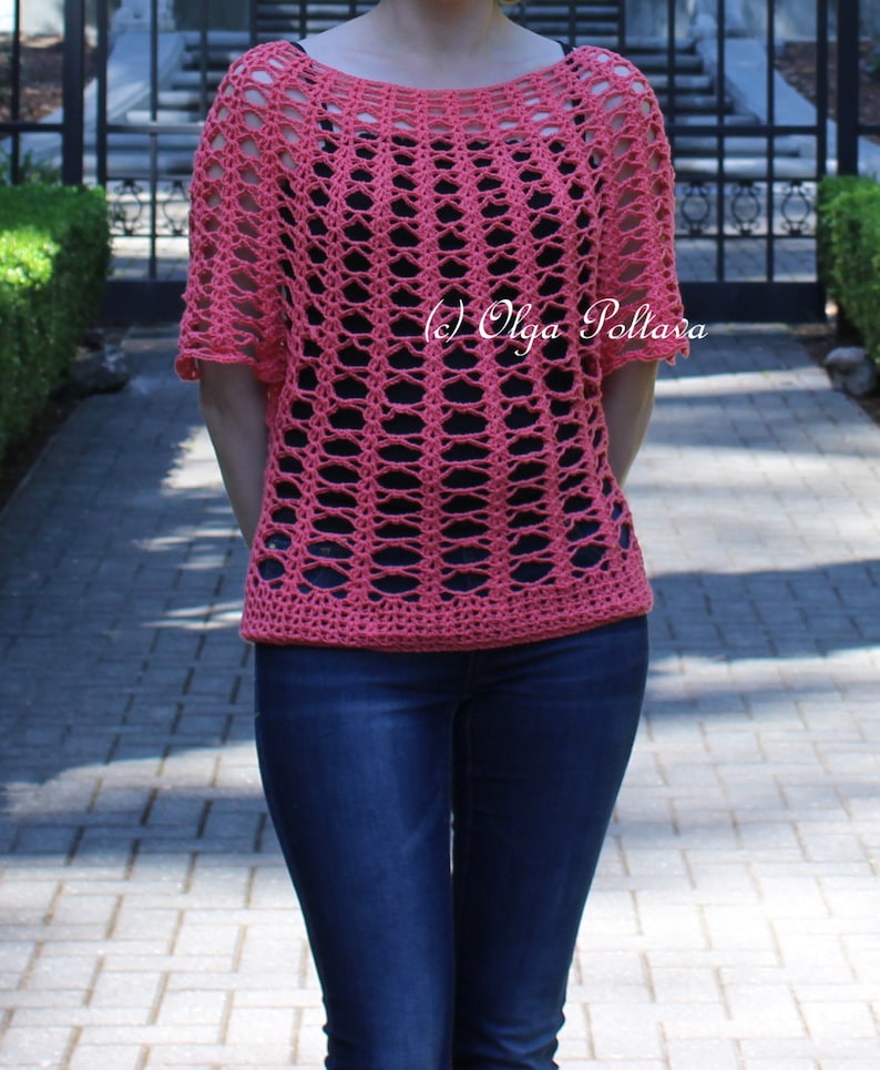 May include: A coral-colored, open-weave crochet top with short sleeves. The top has a boat neck and a loose, airy design. The model is wearing dark blue jeans. The text "(c) Olga Poltava" is visible on the top.