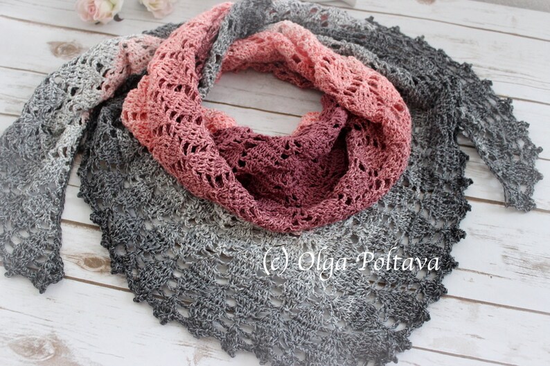 May include: A crocheted shawl with a gradient of grey, pink, and red colors. The shawl is made with a delicate lace pattern and has a scalloped edge.