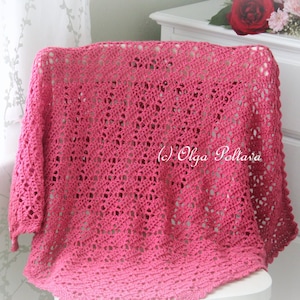 May include: A pink crocheted shawl with a delicate openwork pattern. The shawl is draped over a white chair and has a fringe border.