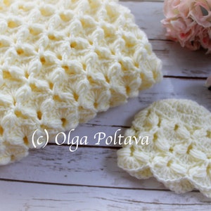 May include: A set of crocheted baby items in a cream color. The set includes a blanket and a hat. The items are made with a delicate, lacy stitch.
