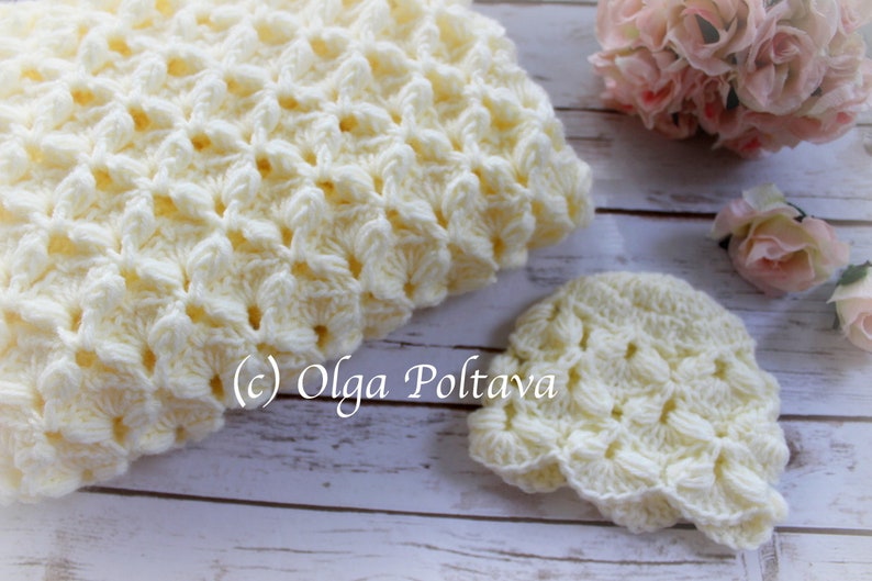 May include: A set of crocheted baby items in a cream color. The set includes a blanket and a hat. The items are made with a delicate, lacy stitch.
