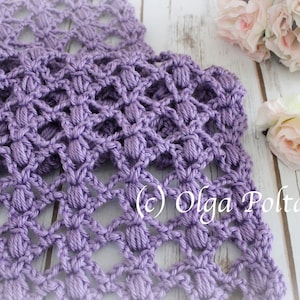 May include: A close-up of a handmade, lavender-coloured crochet scarf with a textured, openwork design. The scarf is made of soft yarn and features a repeating pattern of raised stitches. The background includes flowers and the text "(c) Olga Poltava".