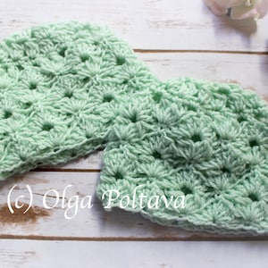 May include: Two mint green crocheted beanies with a floral pattern. The beanies are handmade and sit on a light wooden surface. The copyright symbol and the name "Olga Poltava" are visible on the lower left.