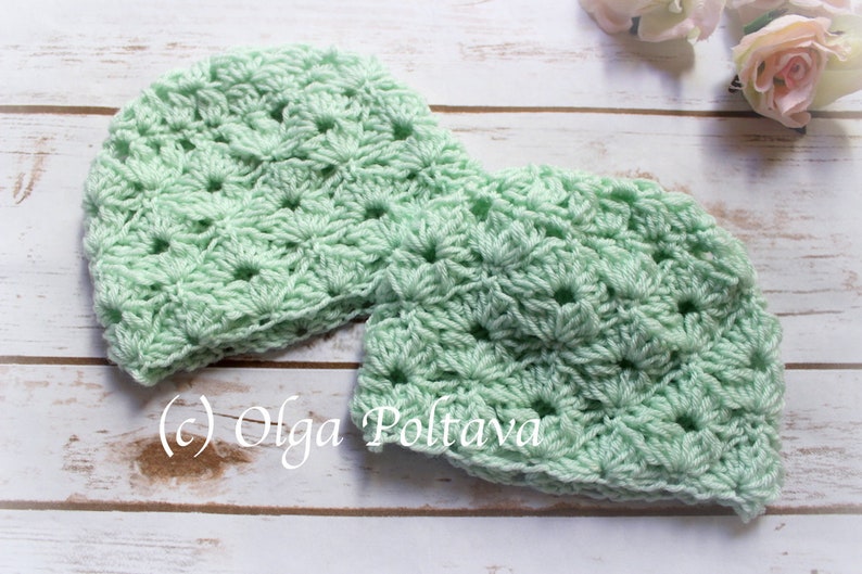 May include: Two mint green crocheted beanies with a floral pattern. The beanies are handmade and sit on a light wooden surface. The copyright symbol and the name "Olga Poltava" are visible on the lower left.