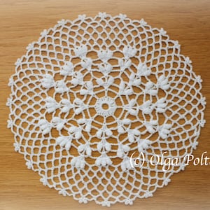 May include: A circular white crochet doily featuring an intricate openwork mesh pattern with small raised floral-like clusters radiating from the center. The text (c) Olga Poltava is printed in the lower right corner of the image.