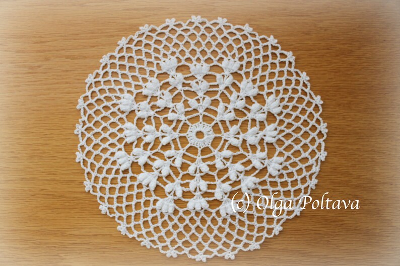 May include: A circular white crochet doily featuring an intricate openwork mesh pattern with small raised floral-like clusters radiating from the center. The text (c) Olga Poltava is printed in the lower right corner of the image.