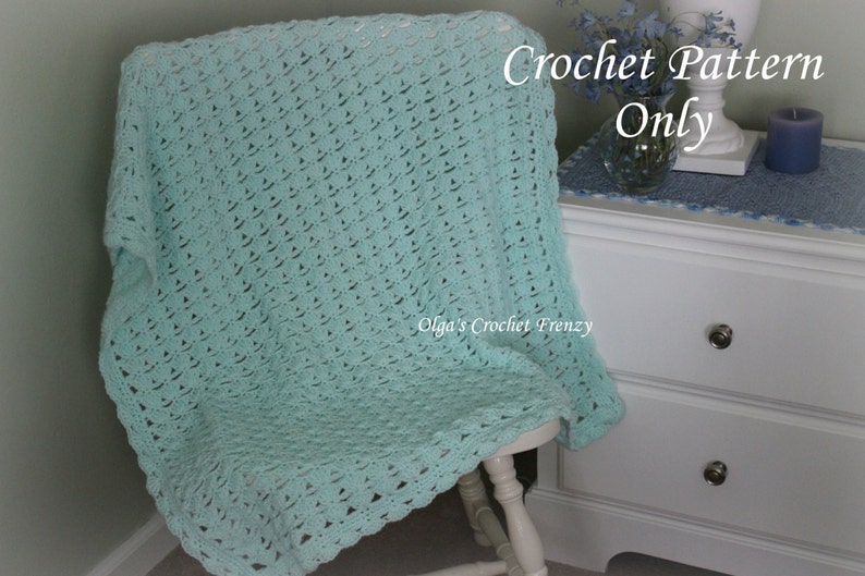 May include: A light blue crochet blanket draped over a white chair. The text "Crochet Pattern Only" is written in white on a blue background. The text "Olga's Crochet Frenzy" is written in white on a blue background.