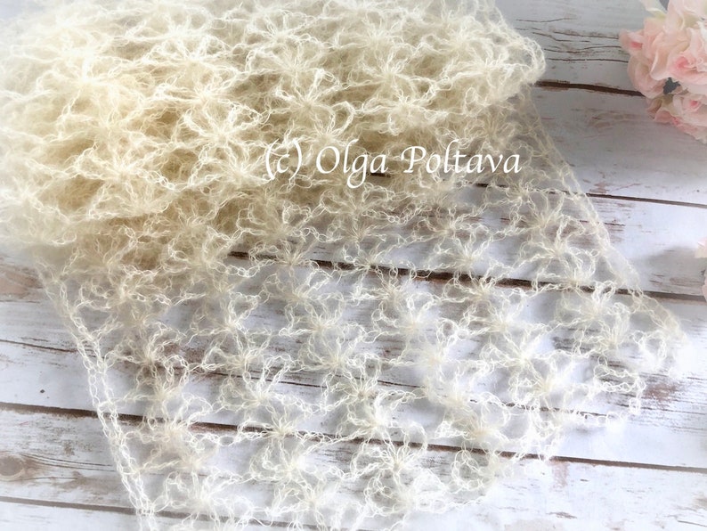 May include: A delicate, off-white crocheted shawl with a floral pattern. The shawl is made of fine yarn and has a soft, airy feel. The text "(c) Olga Poltava" is visible in the image.
