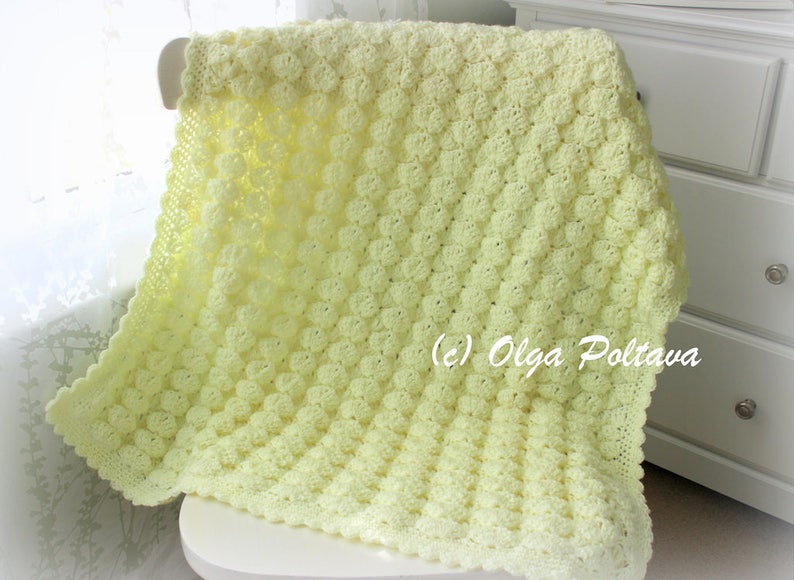 May include: A soft, light yellow crocheted blanket with a textured, raised pattern. The blanket is draped over a white chair and features a scalloped edge. The blanket is approximately 40 inches wide and 50 inches long.