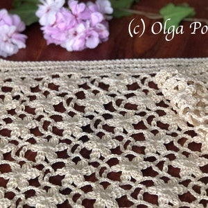 May include: A crocheted table runner with a delicate floral pattern in a cream color. The runner is made with a fine yarn and has a delicate, lacy look.