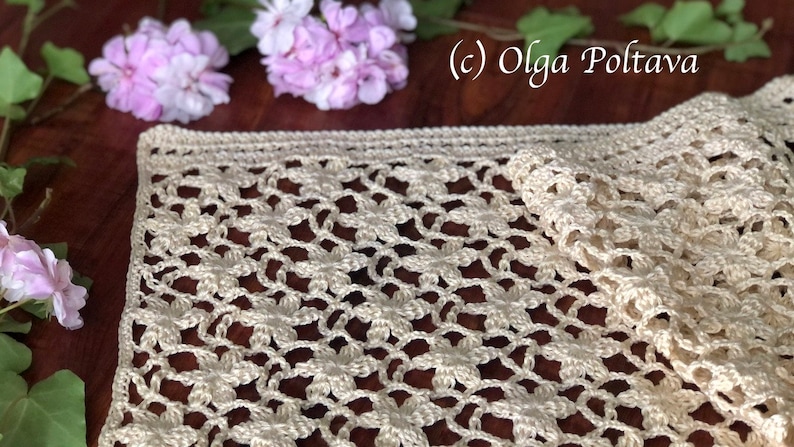 May include: A crocheted table runner with a delicate floral pattern in a cream color. The runner is made with a fine yarn and has a delicate, lacy look.