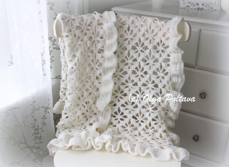 May include: White crocheted shawl with a lacy pattern and ruffled edges. The shawl is draped over a white chair.