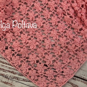 Może przedstawiać: Różowy szal wykonany na szydełku z delikatnym wzorem kwiatowym. Szal jest wykonany z cienkiej przędzy i ma miękką, przewiewną fakturę. (c) Olga Poltava