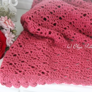 May include: A close-up of a pink crocheted shawl with a scalloped edge. The shawl is made with a delicate stitch pattern and has a soft, feminine look.