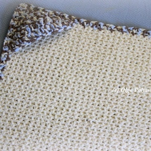 May include: A crocheted baby blanket in cream with a brown and blue border.