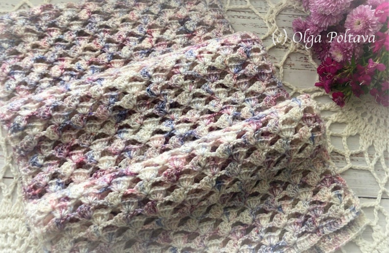 Pu&ograve; includere: Uno scialle all'uncinetto in uno schema di colori bianco, rosa e blu. Lo scialle &egrave; realizzato con un punto delicato e traforato e ha una texture morbida e fluida.