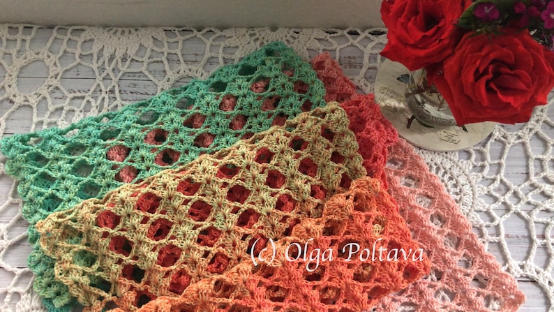 Pode incluir: Tr&ecirc;s xales de croch&ecirc; em tons de verde, laranja e rosa s&atilde;o sobrepostos em uma toalha de mesa de renda branca. O design de trama aberta dos xales cria uma apar&ecirc;ncia delicada e arejada. O aviso de direitos autorais "(c) Olga Poltava" &eacute; vis&iacute;vel na parte inferior da imagem.