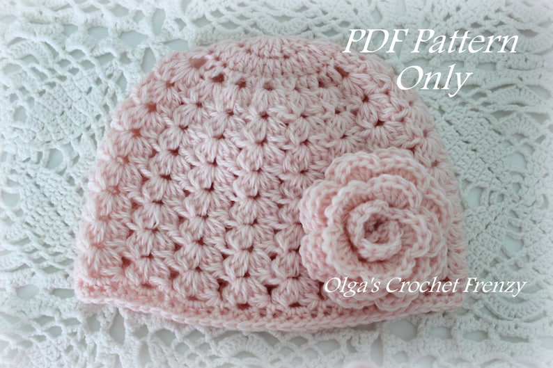 May include: A pink crocheted hat with a matching flower embellishment. The hat is made with a delicate stitch pattern and has a soft, feminine look. The text "PDF Pattern Only" and "Olga's Crochet Frenzy" are visible in the image.