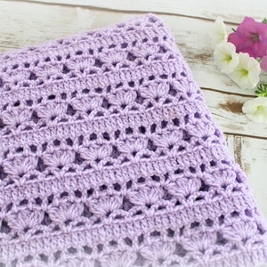May include: A lavender crochet baby blanket with a delicate, lacy pattern. The blanket is soft and cozy, perfect for a newborn.