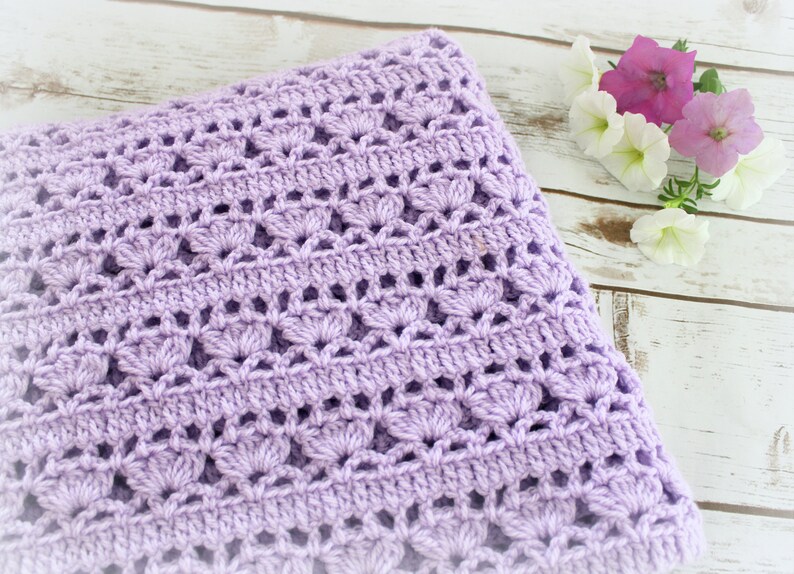 May include: A lavender crochet baby blanket with a delicate, lacy pattern. The blanket is soft and cozy, perfect for a newborn.
