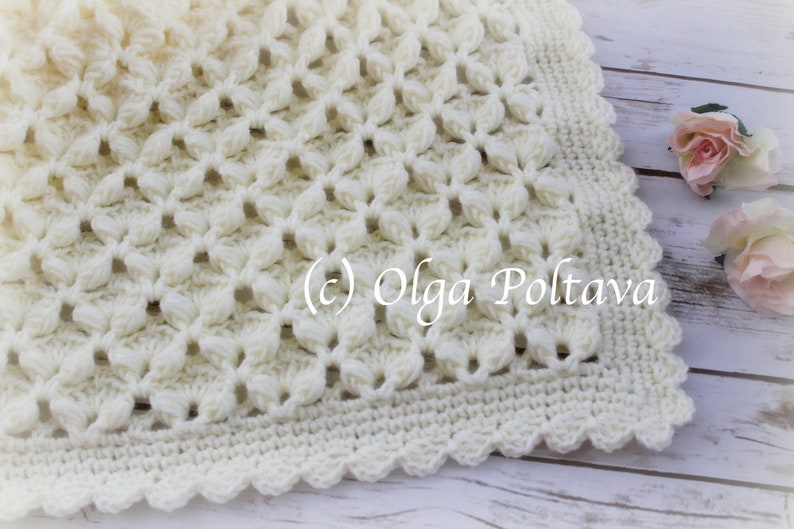 May include: A white crocheted baby blanket with a delicate floral pattern and a scalloped border. The blanket is made with soft yarn and is perfect for a newborn baby.