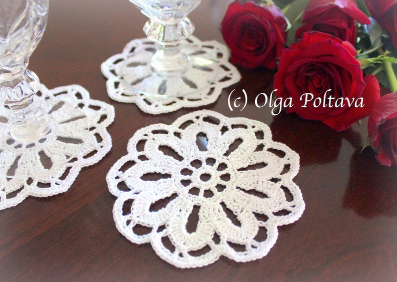 May include: Three white crocheted doilies on a wooden table with red roses. (c) Olga Poltava
