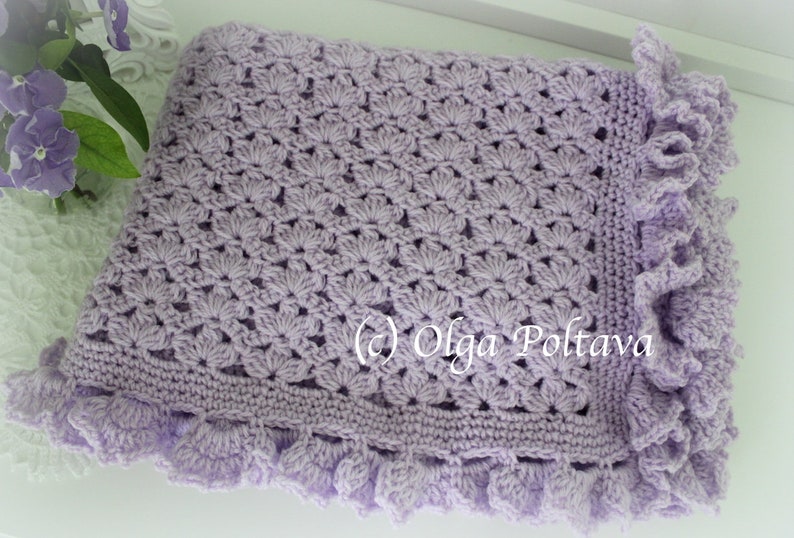 May include: A lavender crochet baby blanket with a scalloped edge. The blanket is made with a delicate stitch pattern and has a soft, fluffy texture.