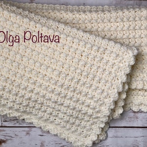 Puede incluir: Una manta de beb&eacute; de ganchillo blanco con un borde festoneado. La manta est&aacute; doblada por la mitad y tiene un patr&oacute;n texturizado. El texto (c) Olga Poltava es visible en la imagen.