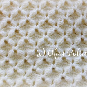 May include: Close-up of a white crocheted fabric with a repeating pattern of small flowers. The fabric is textured and has a delicate, airy feel. (c) Olga Poltava