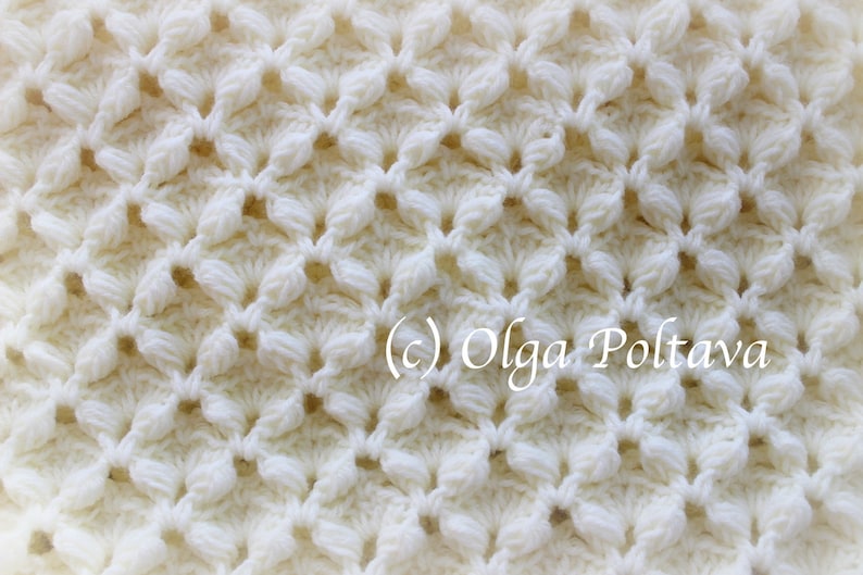May include: Close-up of a white crocheted fabric with a repeating pattern of small flowers. The fabric is textured and has a delicate, airy feel. (c) Olga Poltava