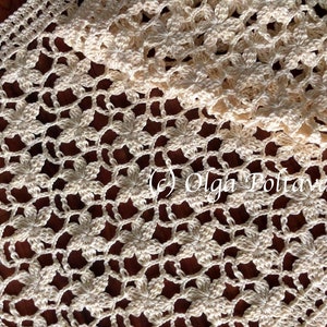 May include: A crocheted table runner with a delicate floral pattern in a cream color. The runner is made with a fine yarn and has a delicate lace border.