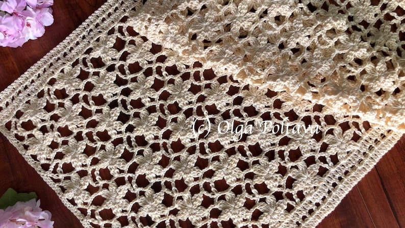 May include: A crocheted table runner with a delicate floral pattern in a cream color. The runner is made with a fine yarn and has a delicate lace border.