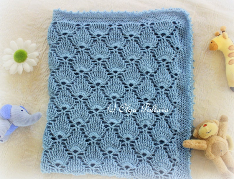 May include: A light blue crocheted baby blanket with a delicate, lacy pattern. The blanket is made with a soft yarn and has a scalloped edge.