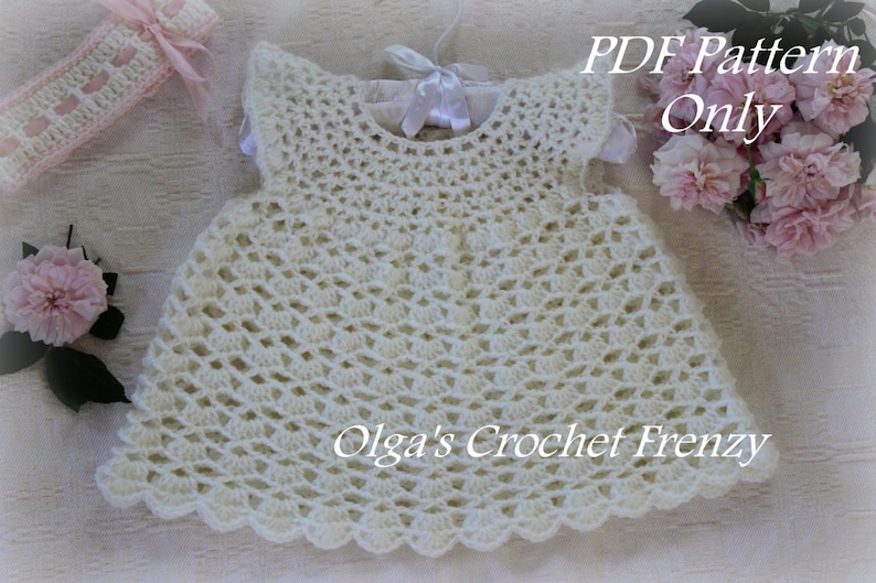 May include: White crochet baby dress with a scalloped hem. The dress has a simple design with a round neckline and sleeveless style. The text "PDF Pattern Only" and "Olga's Crochet Frenzy" is visible in the image.