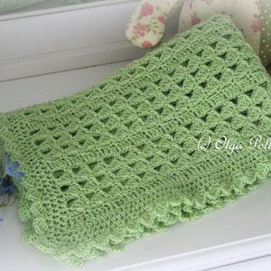 May include: A green crocheted baby blanket with a delicate, lacy pattern. The blanket has a scalloped edge and is made with a soft, lightweight yarn.