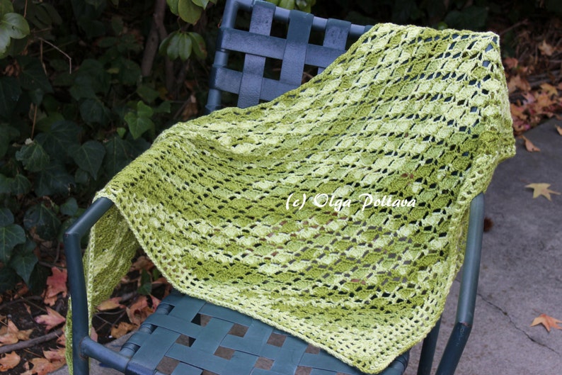 May include: A triangular crochet shawl featuring a variegated yarn pattern in shades of lime green, olive, and dark forest green. The textile displays an openwork diamond stitch pattern with a solid border. The text (c) Olga Poltava is visible.