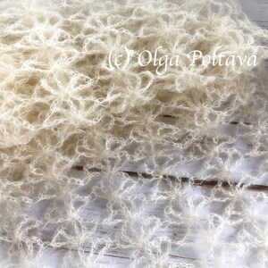 May include: A white crocheted shawl with a delicate, lacy pattern. The shawl is made of a soft, lightweight yarn and has a flowing, ethereal look.
