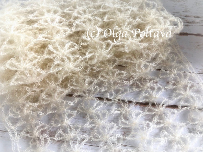 May include: A white crocheted shawl with a delicate, lacy pattern. The shawl is made of a soft, lightweight yarn and has a flowing, ethereal look.