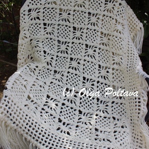 May include: A white crocheted throw blanket with fringe. The blanket is made with a delicate, lacy pattern and has a soft, textured feel. (c) Olga Poltava