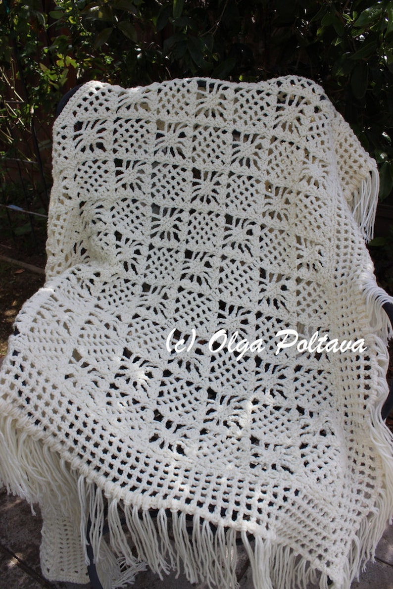May include: A white crocheted throw blanket with fringe. The blanket is made with a delicate, lacy pattern and has a soft, textured feel. (c) Olga Poltava
