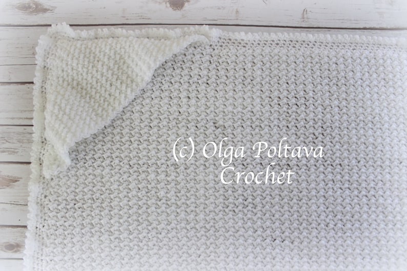 May include: A white crocheted blanket with a textured stitch pattern. The blanket is folded in half with a corner folded over. The text (c) Olga Poltava Crochet is visible in the image.