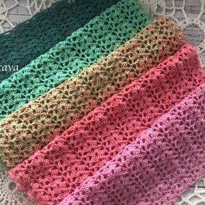 K&ouml;nnte beinhalten: Ein Set aus sechs geh&auml;kelten Decken in verschiedenen Gr&uuml;nt&ouml;nen, Gelb, Orange, Rosa und Lila. Die Decken sind in einem Regenbogenmuster angeordnet und mit einer zarten Lochmuster-Masche gearbeitet.