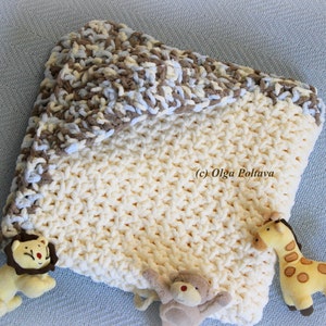 May include: A crocheted baby blanket in cream with a brown, blue, and cream striped border. The blanket has a lion, monkey, and giraffe plush toy attached.