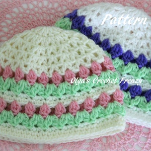 Puede incluir: Dos gorros de ganchillo. Uno es de color crema con detalles en rosa y verde. El otro es blanco con detalles en morado y verde. El texto "Pattern Only" es visible en el gorro blanco. Los gorros est&aacute;n hechos a mano.