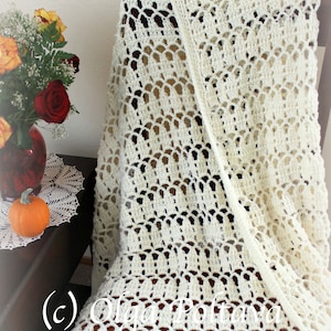 May include: A white crocheted throw blanket with a delicate, lacy pattern. The blanket is draped over a chair and has a subtle sheen.